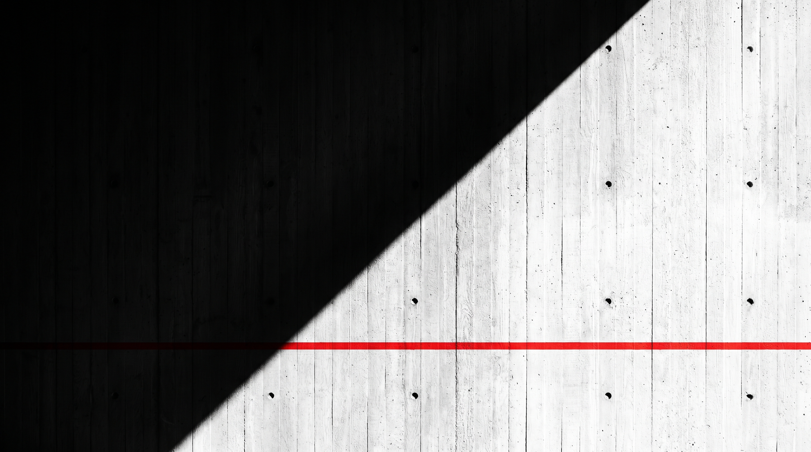 Brutalist concrete wall with diagonal light and red horizontal line