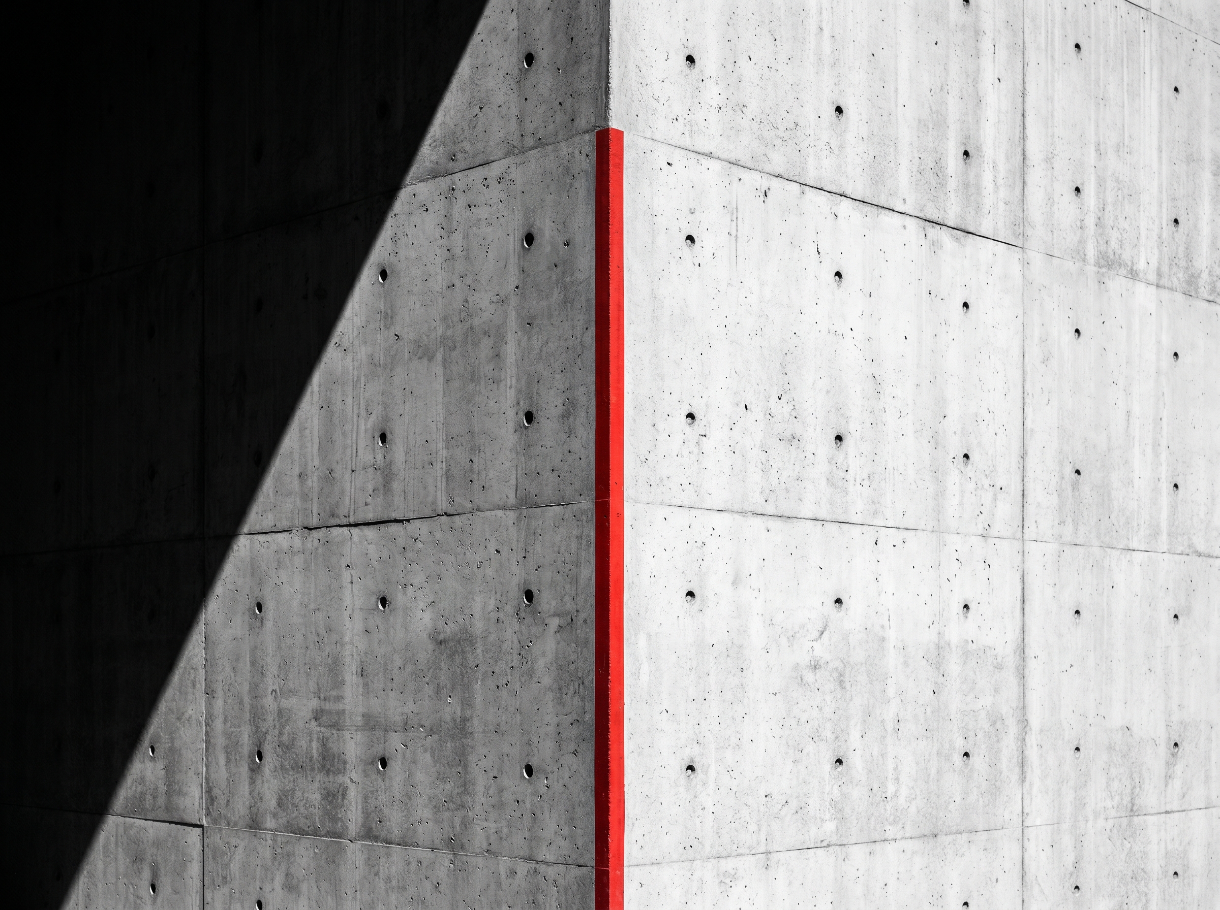 Brutalist concrete wall with a single red vertical stripe — the line between leak and closed