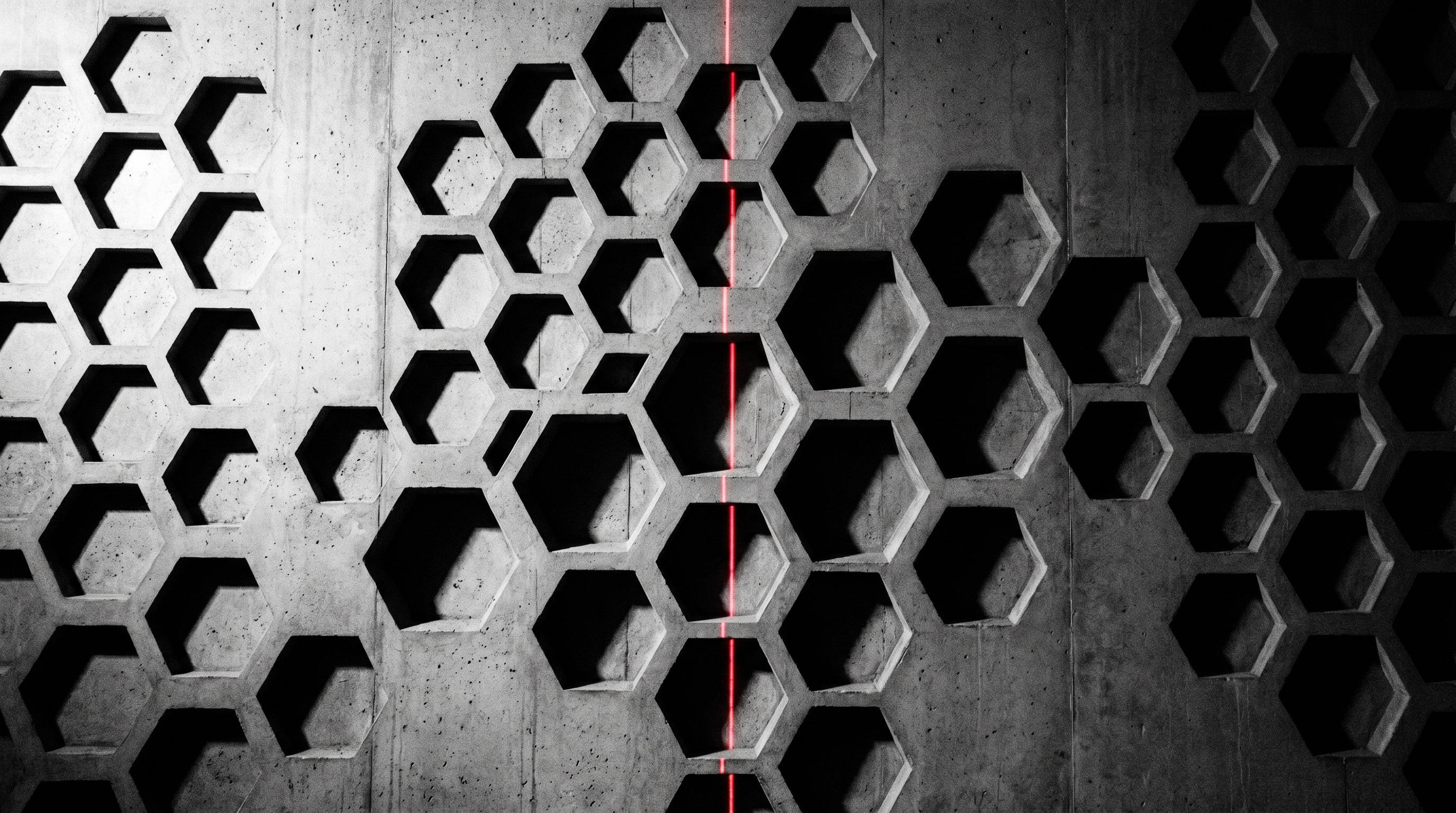 Brutalist concrete wall with hexagonal honeycomb relief pattern and a single red vertical laser stripe