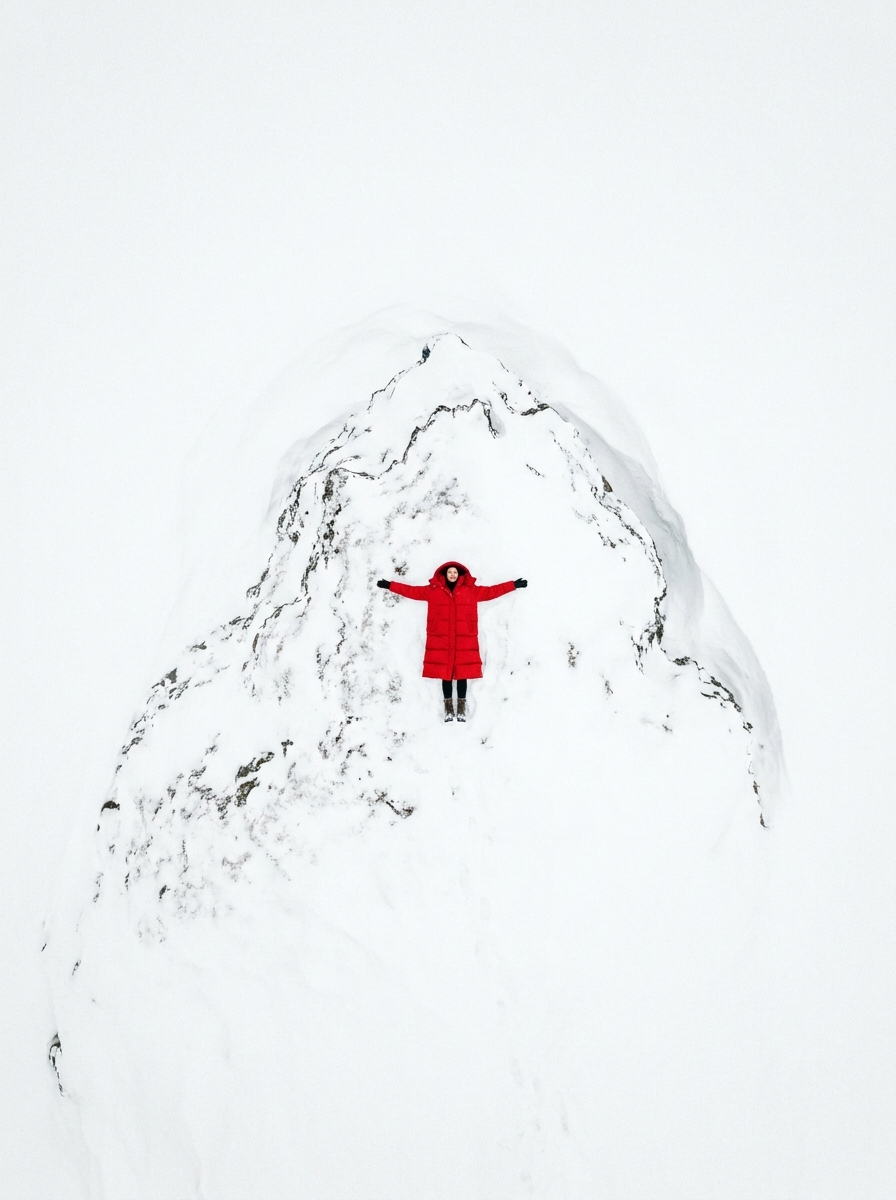 Overhead shot of a model in a red puffer coat on snow
